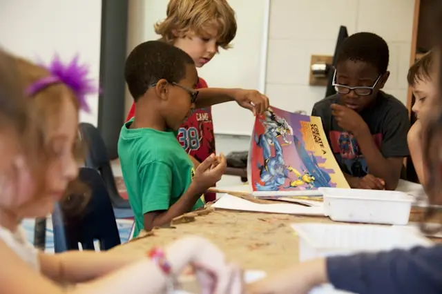 Diverse group of kids learning at table.