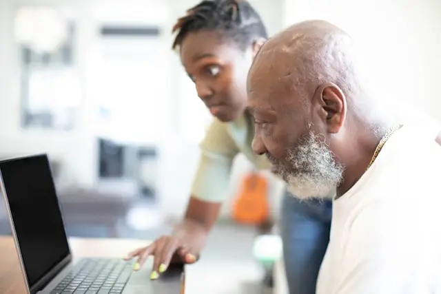 Senior getting help using laptop.
